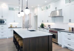 beautiful kitchen in new luxury home with large island, pendant lights, oven, range, and hardwood floors.
