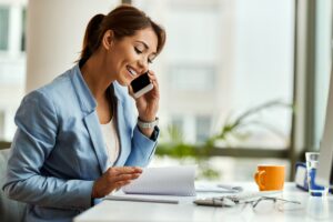 Happy,Businesswoman,Talking,On,Mobile,Phone,While,Analyzing,Weekly,Schedule