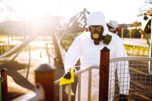 Man wearing protective suit washes and disinfecting playground to preventing the spread of epidemic