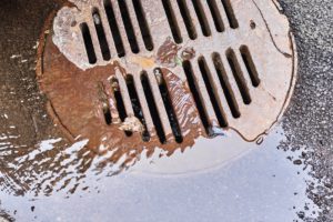 Water draining into a sewer manhole after rain on the city street